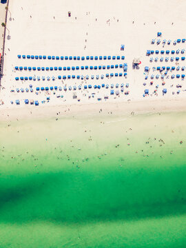 Aerial view of sunbeds and umbrellas placed on wide sandy beach