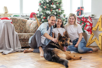 happy family and cute dog having fun at christmas tree. atmospheric emotional moments. merry christmas and happy new year concept.