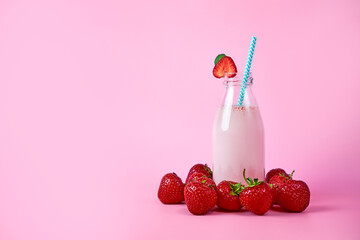 Strawberry smoothie or milkshake in glass jar with berries on pink background. Healthy summer drink