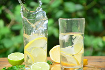 Fresh summer drink. Cold lemonade with mint lemon and lime on a nature outdoor background. Mojito summer refreshing cocktail with ice and mint