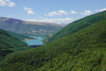 Panorama of the Fiastra Lake on the Sibillini Mountains in Marche. The lake is in the middle of a green forest. Italy