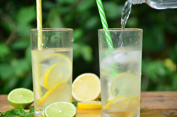 Fresh summer drink. Cold lemonade with mint lemon and lime on a nature outdoor background. Mojito summer refreshing cocktail with ice and mint