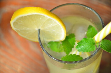 Fresh summer drink. Cold lemonade with mint lemon and lime on a nature outdoor background. Mojito summer refreshing cocktail with ice and mint