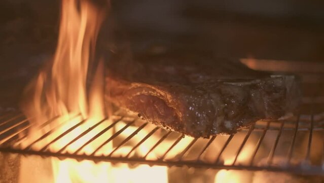 Close-up of big stake grilled on the big open fire and turned with tongs