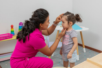 Pediatrician rewards a girl who is in his office, placing a star of good conduct on her forehead