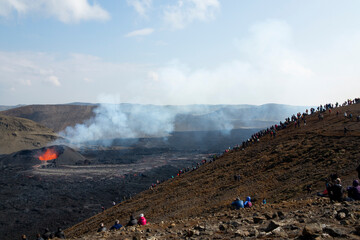 Fototapeta na wymiar MERADALIR, ICELAND - AUGUST 14, 2022: A volcanic eruption has started at Fagradalsfjall in the Reykjanes peninsula. It attracts thousands of visitors every day who brave a daring hike to the crater.