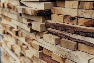 Stacked rough unhewn boards. Freshly sawn wood, raw material, concept of renewable fuel. Selective focus, natural background
