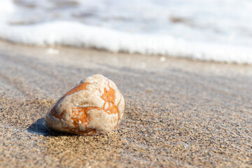 Natural stone in white and yellow colors in the water on the beach.