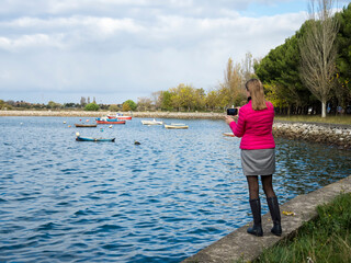 young woman in red coat taking photos to the boats