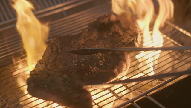 Close-up of big stake grilled on the big open fire and turned with tongs