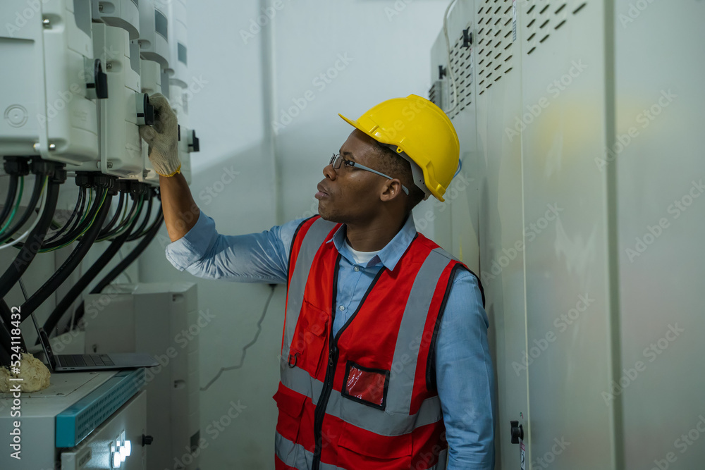 Poster engineer checking the electrical system with panel in control or server room.