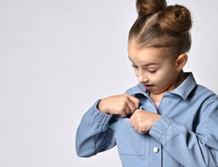 close up photo of a baby girl taking out or hiding something in the breast pocket of her spring...