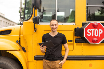 Portrait of teacher standing near the school bus.