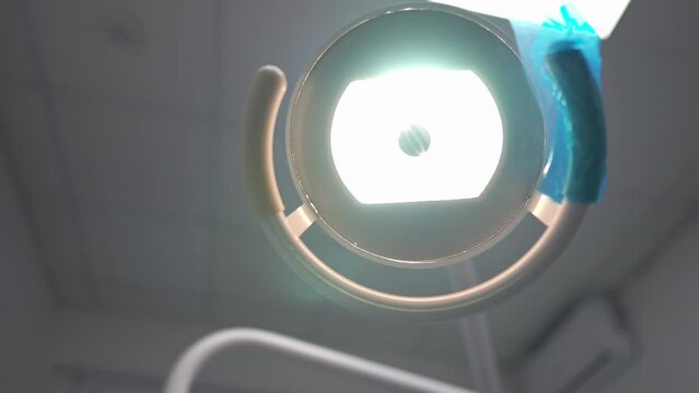 Close-up dental lamp turning on with female hand adjusting equipment in hospital. Unrecognizable Caucasian dentist preparing device for medical examination in dental clinic. Health care and medicine