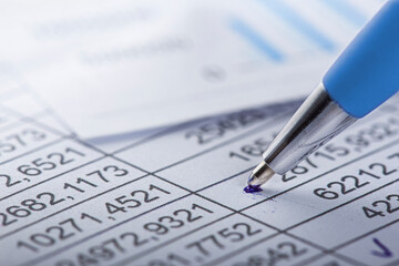 Accounting document with pen, money, coins and checking financial chart. Concept of banking, financial report and financial audit.