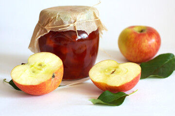 Apple cut in half, fresh green leaves, a jar of homemade jam and whole fruit. Sweet, tasty, diet, canned, organic food, cooking  breakfast, healthy vegetarian dessert. Autumn season concept background