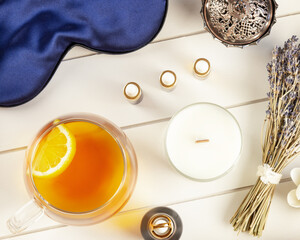 Self-care flat lay with blue sleeping mask, lavender flower, herbal tea with lemon and natural oils on a white wooden tray. Concept of Me time and no depression. Remedy for healthy sleep