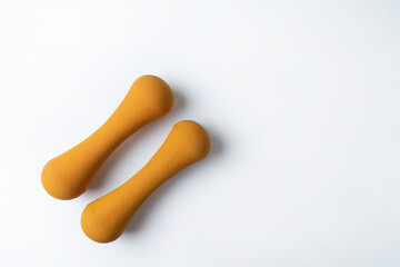 Two orange fitness dumbbells lying on the white background