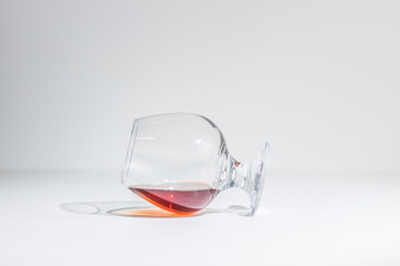 a glass of cognac is lying on its side. on a white background