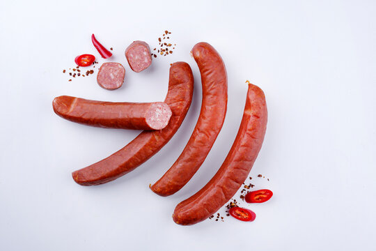 Traditionelle rohe bayrische scharfe Bratwurst mit Chili angeboten als Draufsicht auf wei&szlig;em  Board mit Textfreiraum 