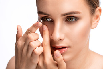 Beautiful young woman holding a contact lens on her finger. Eye care and choice of means to improve...