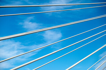 Cables of a bridge with bright blue sky and a few clouds