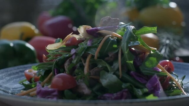 Close-up of fresh salad made of red cabbige, tomatoes, onions, basil, arugula and pieces of fried meat