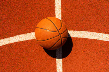 Top view orange ball for basketball lying on the rubber sport court. Sport red ground outdoor in...