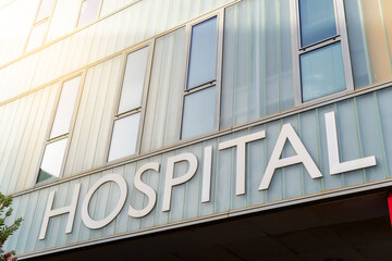 Hospital building sign closeup, with sky reflecting in the glass, healthcare and medicine concepts