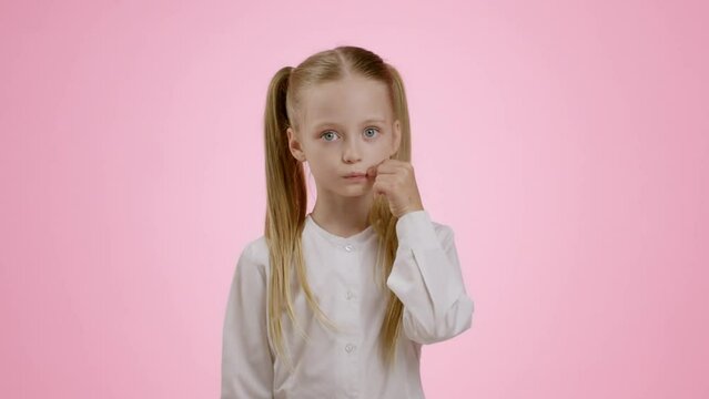 Kids and privacy. Studio portrait of mysterious little girl with ponytails zipping her lips and showing hush gesture
