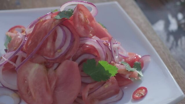 Close-up of fresh salad made of red cabbige, tomatoes, onions, basil, arugula and pieces of fried meat