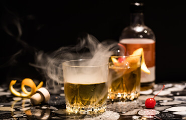 Smoke pouring out of an old fashioned cocktail. Selective focus front of glass.