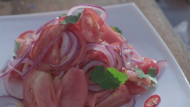 Close-up of fresh salad made of red cabbige, tomatoes, onions, basil, arugula and pieces of fried meat