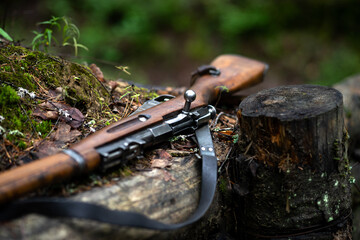 A Finnish rifle from the Second World War lies in the forest on the parapet of the trench. Weapons of the Finnish army. A wooden rifle with a bolt. - obrazy, fototapety, plakaty