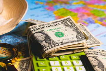 Notas de dólares dos Estados Unidos sobre um mapa com uma calculadora, chapéu de sol e uma lupa...