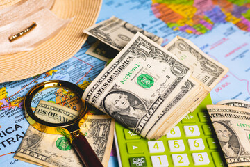 Notas de dólares dos Estados Unidos sobre um mapa com uma calculadora, chapéu de sol e uma lupa...