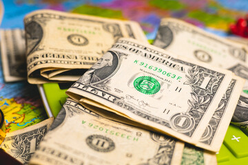 Notas de dólares dos Estados Unidos sobre um mapa com uma calculadora, chapéu de sol e uma lupa na composição da imagem. Conceitos de orçamento para viagem, férias e câmbio.