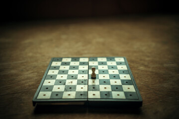 A lonely figure on a retro-style chessboard. A white pawn on the chessboard. Playing alone.The...
