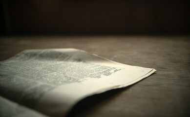 An old paper newspaper on a wooden table in vintage processing. Reading the news. Printed edition...