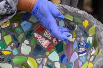 People decorate earthenware with mosaic techniques in the master class or in the fresh air in the workshop. Homemade mosaic flower pot with porcelain pieces.