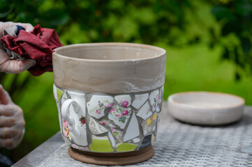 People decorate earthenware with mosaic techniques in the master class or in the fresh air in the workshop. Homemade mosaic flower pot with porcelain pieces.
