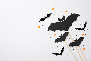 Halloween party decorations concept. Top view photo of bat silhouettes and confetti on isolated white background with empty space
