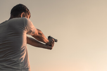 A man with a gun in his hands takes aim. Shooting in the street, crime. copy space