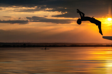 Kind macht Rückwärtssalto in einem See bei Sonnenuntergang