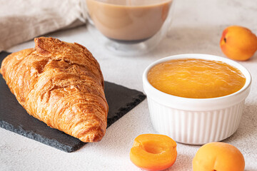 Fresh croissant with apricot jam and coffee. French breakfast concept