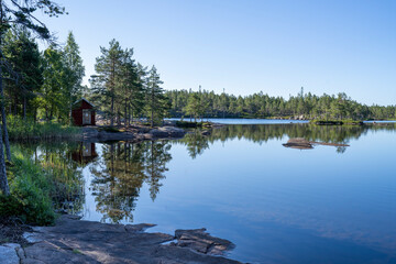Obraz premium Stunning view of Serene and Reflecting Lake Tarnattvattnen and Remote hiking Resting Cottage in Skuleskogen National Park on a Summertime Evening with gorgeous background of Slattdalsskrevan. 