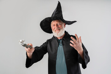 old wizard man  shows magic wand in a Halloween costume, on a white background