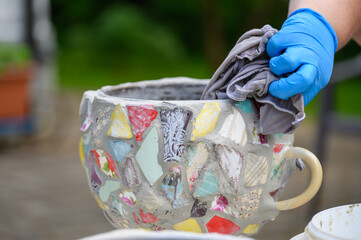 People decorate earthenware with mosaic techniques in the master class or in the fresh air in the workshop. Homemade mosaic flower pot with porcelain pieces.