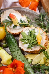 Country breakfast concept with bread, kitchen garden vegetables, herbs and edible flowers, close up.