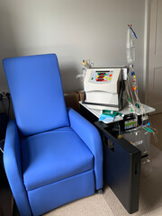 Home hemodialysis machine with all the tubes and fluids set up prepared to start and blue chair